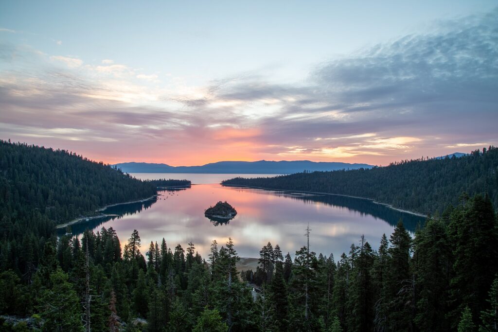 Emerald Bay and the clear blue water of Lake Tahoe surrounded by pine-covered mountains