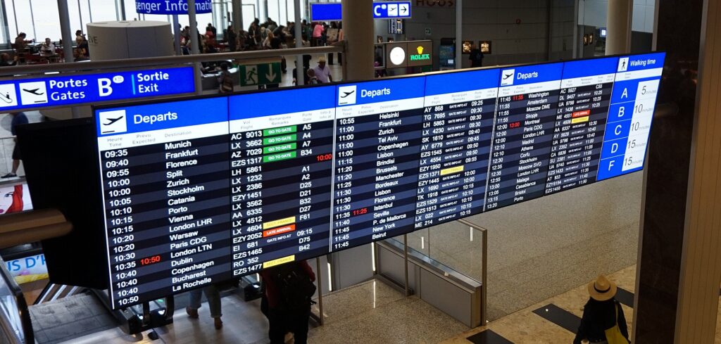 A flight departure board at Geneva Airport listing destinations, times and gates