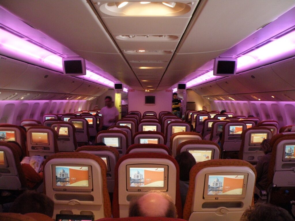 An economy class airplane cabin with dimmed violet mood lighting on a long-haul flight