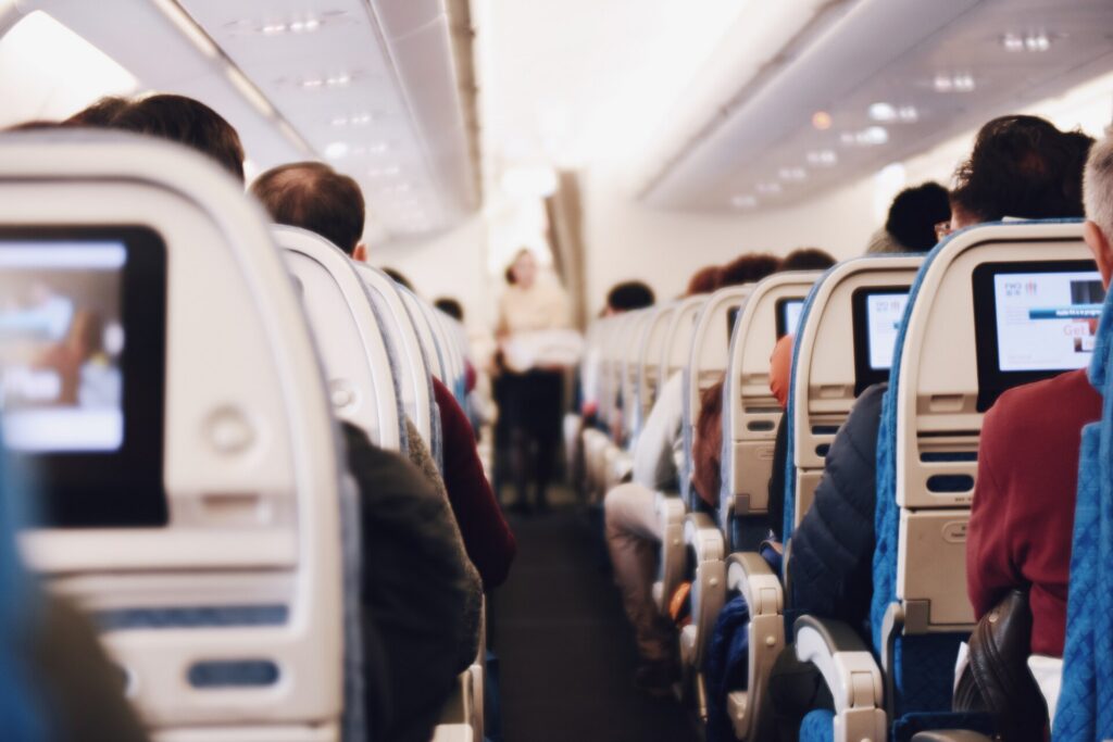 The aisle of an airplane cabin during a flight, with seatback screens on both sides