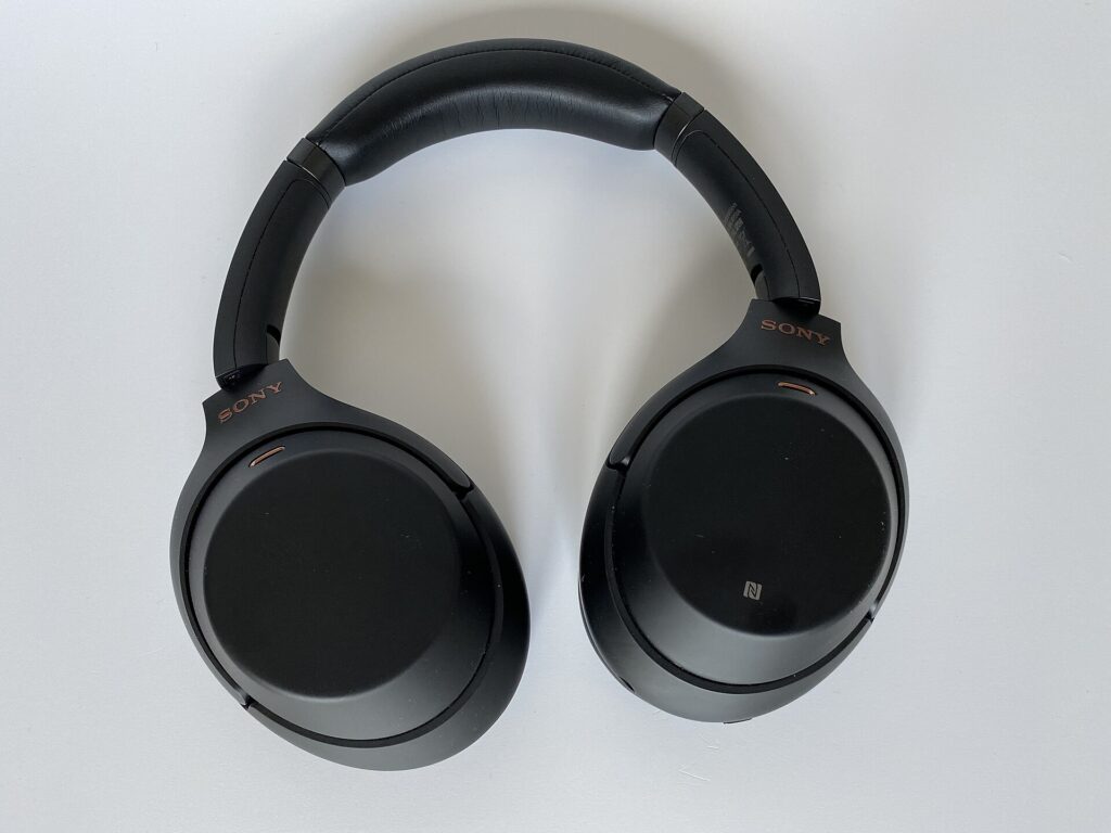 A pair of black over-ear wireless noise-cancelling headphones lying flat on a white surface