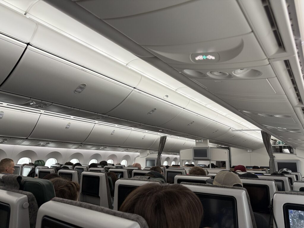 The economy cabin of a widebody Boeing 787 with rows of seats and overhead bins