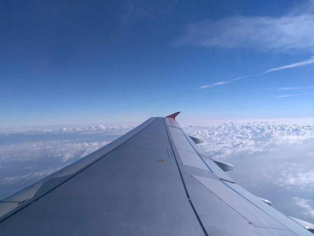 An airplane wing above the clouds seen from a passenger window