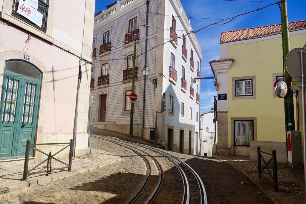 A yellow Tram 28 climbing a narrow street in Lisbon's Alfama district