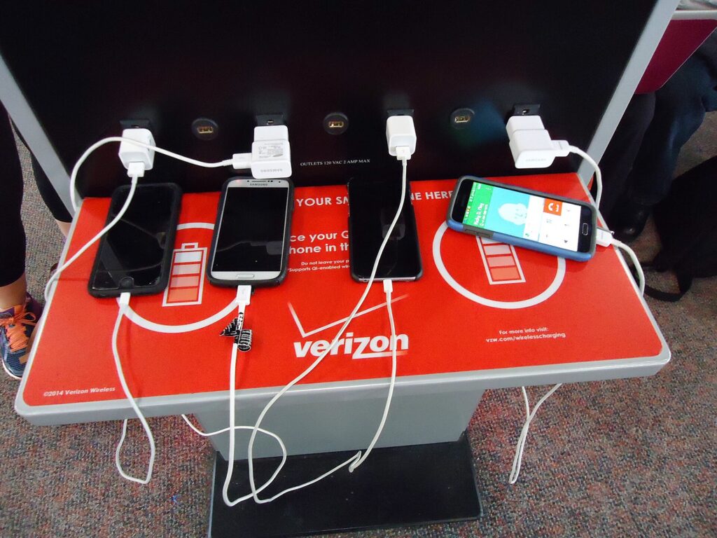 Several phones plugged into a public charging station at an airport