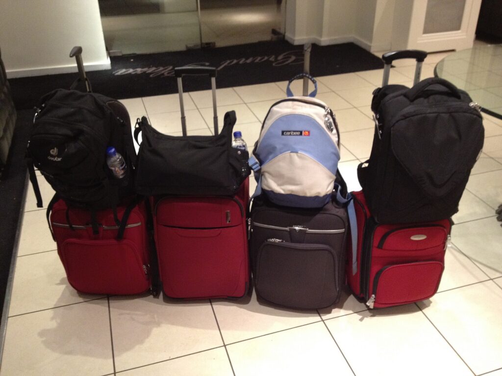 Backpacks balanced on top of rolling carry-on suitcases in a hotel lobby