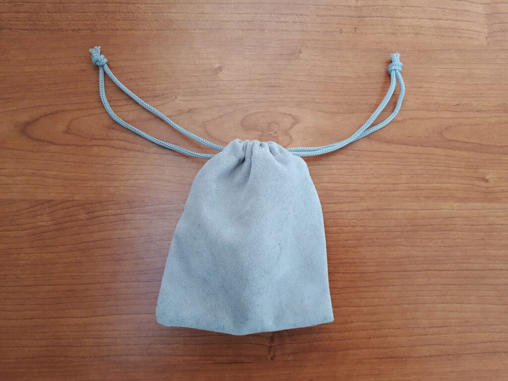 A small gray fabric drawstring pouch on a plain background