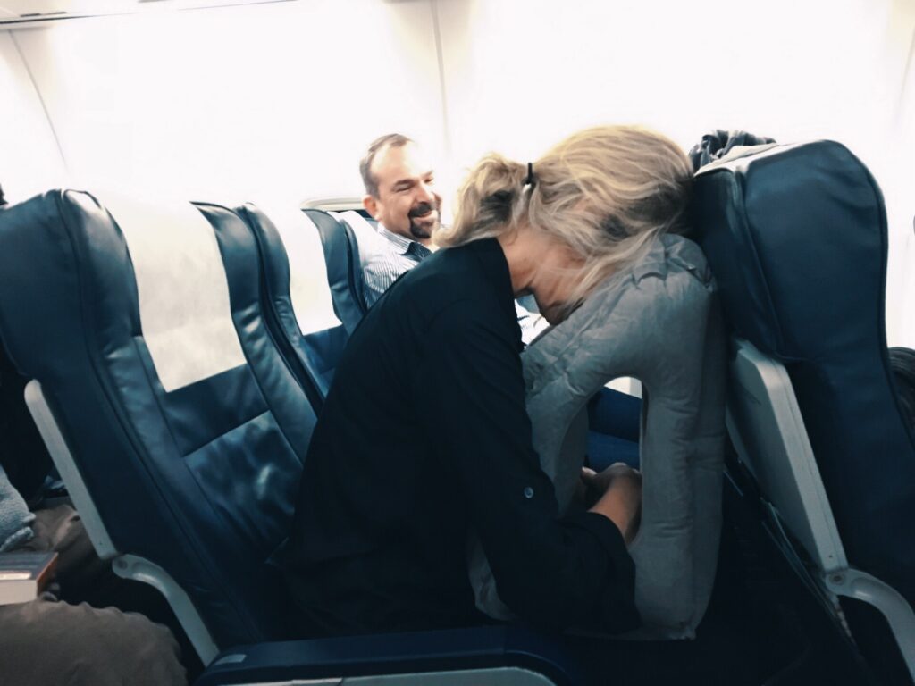 A gray inflatable travel pillow lying on a woven mat