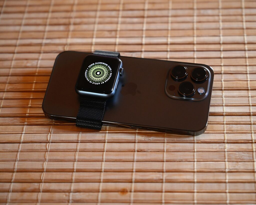 An Apple Watch resting on an iPhone on a bamboo mat