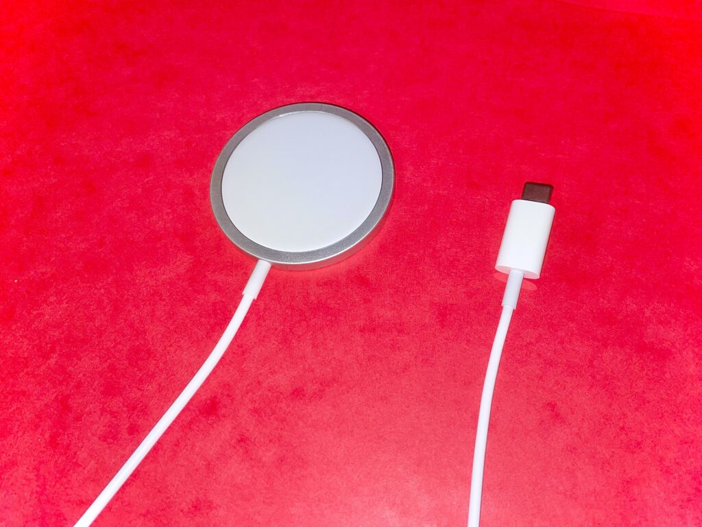 A round magnetic MagSafe charging puck with its USB-C cable