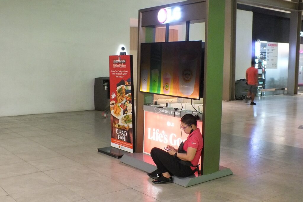 A traveler charging a phone at a charging kiosk in an airport terminal