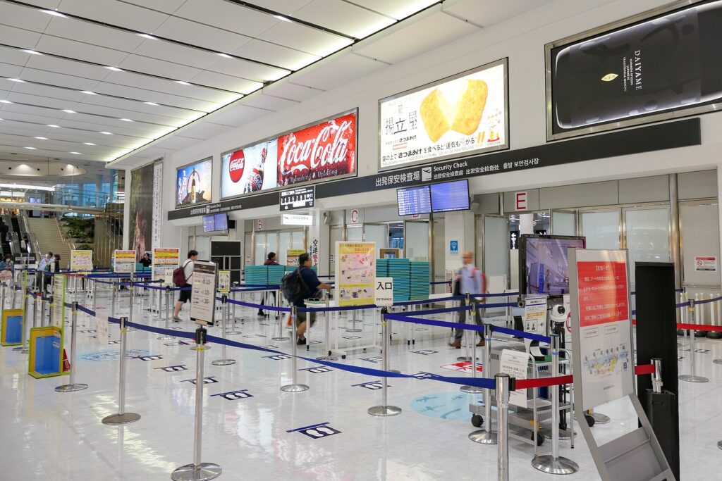 Passengers approaching an airport security checkpoint with screening lanes