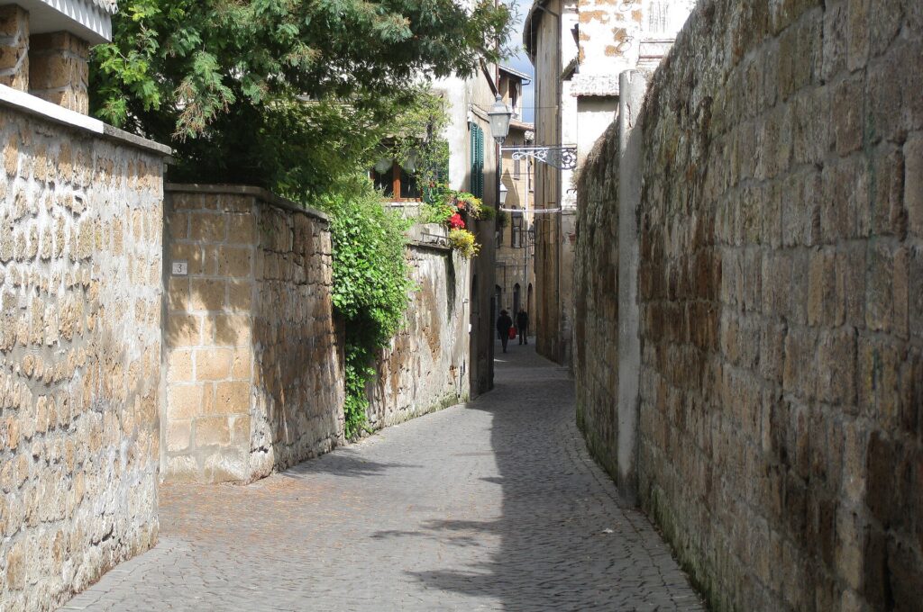 A narrow cobblestone street between stone buildings in an Italian hill town