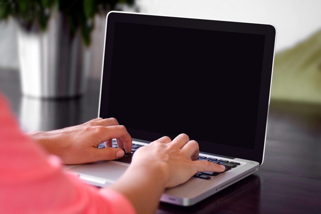 Hands typing on a laptop keyboard while comparing options online