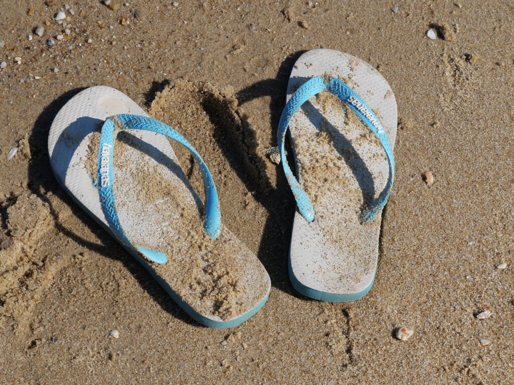 A pair of rubber flip-flops on a sandy beach