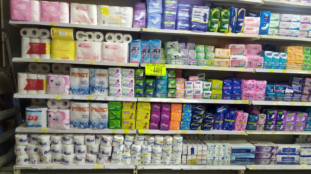 A supermarket shelf stocked with sanitary pads, tampons and toilet paper