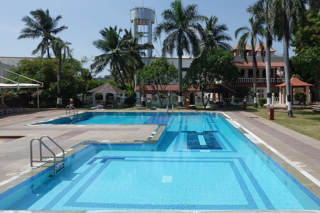 A resort hotel swimming pool surrounded by loungers and palm trees