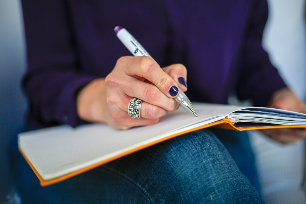 A person writing notes by hand in a notebook
