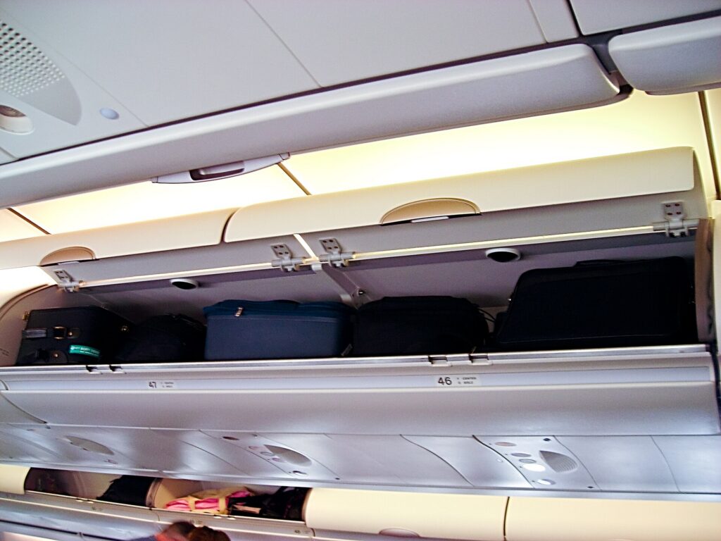 Open overhead luggage compartments above economy seats on an Airbus