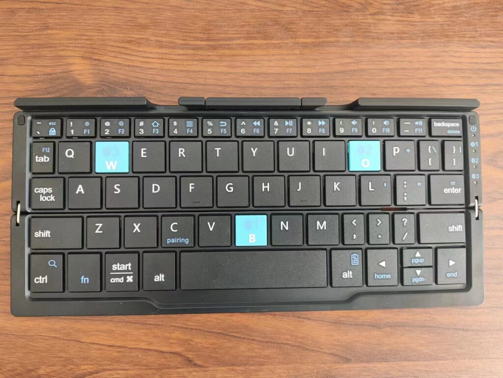 A compact folding Bluetooth keyboard opened on a wooden table