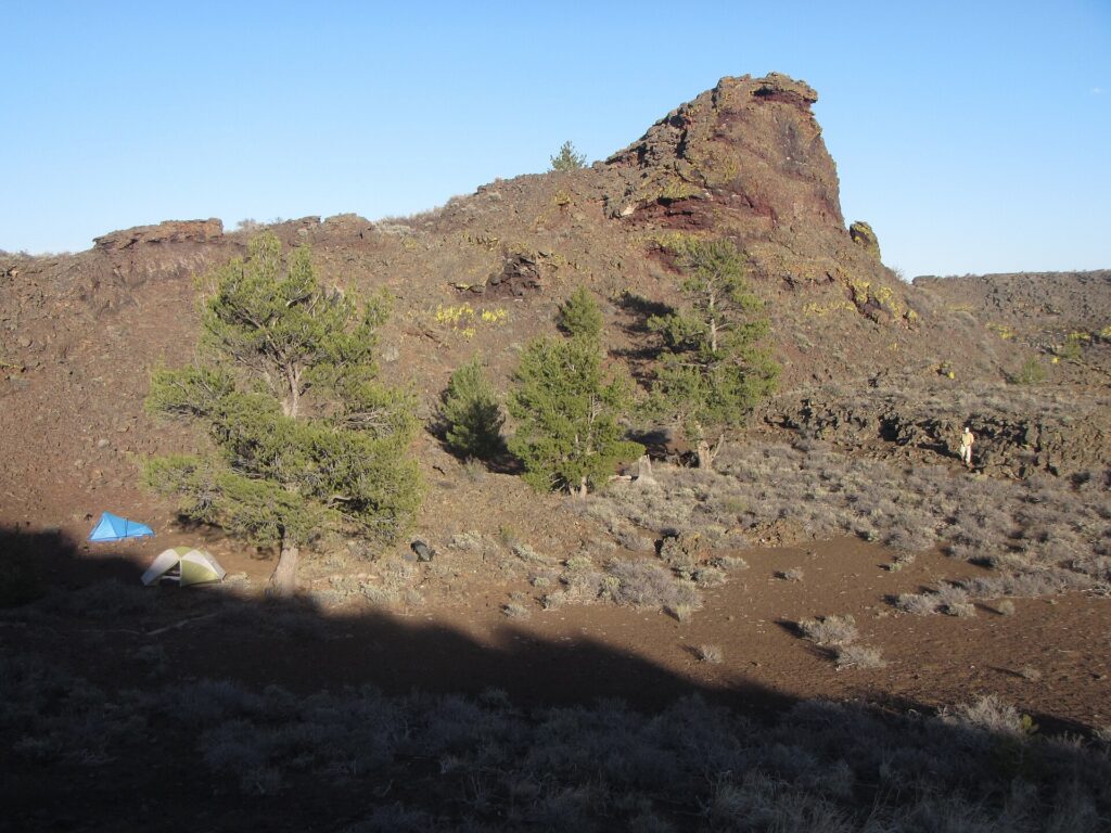 Two tents pitched in a sheltered volcanic crater at a backcountry campsite