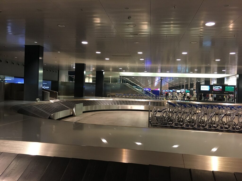 An empty baggage claim carousel in an airport arrivals hall