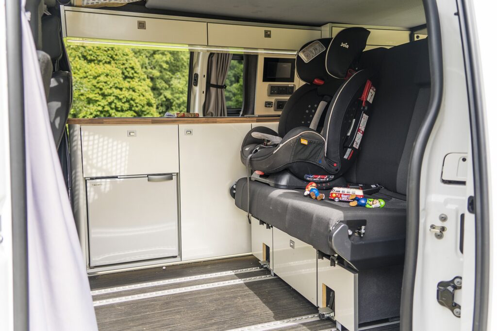 A child's car seat installed in the back of a camper van