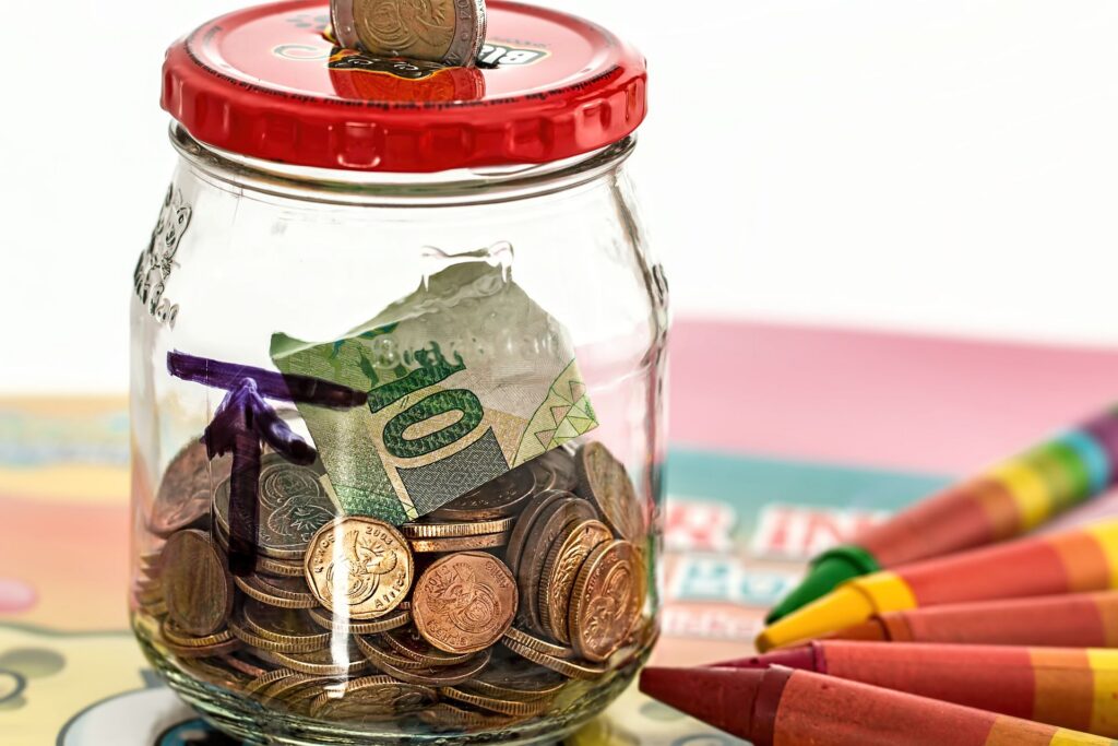 A glass-jar piggy bank holding coins saved for a trip