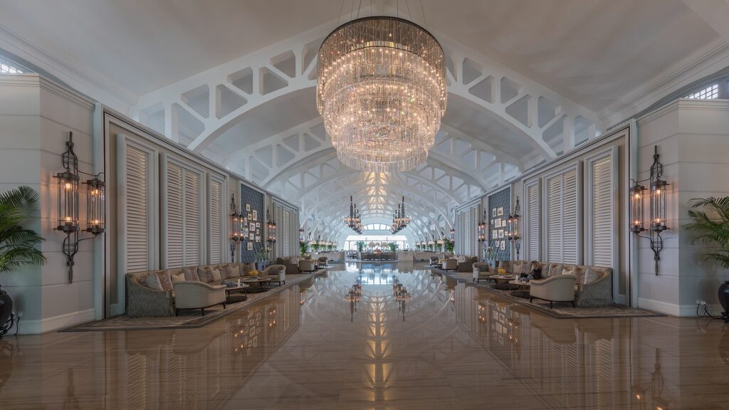 A spacious hotel lobby with couches, rugs and a chandelier